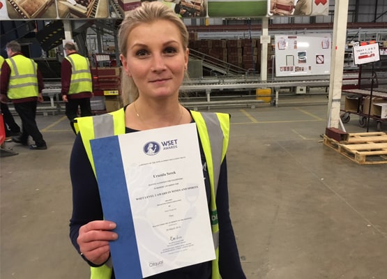 Lady in a warehouse holding up her WSET certificate